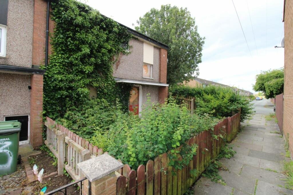Three-bedroom house in Wirral on sale for £45,000, hidden under weeds and debris. Perfect for those seeking a renovation project with potential for significant value increase.