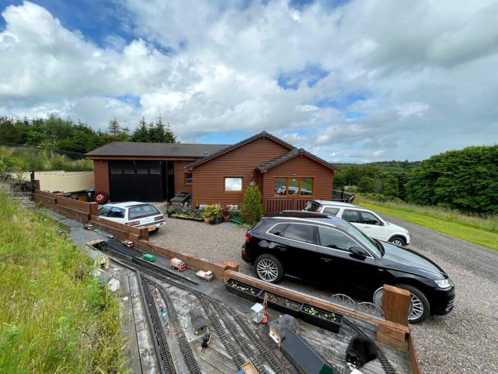 A quirky £300,000 bungalow near Kinross, Scotland, features a full model railway around the driveway, spacious living areas, two bedrooms, and a huge garage with conversion potential.