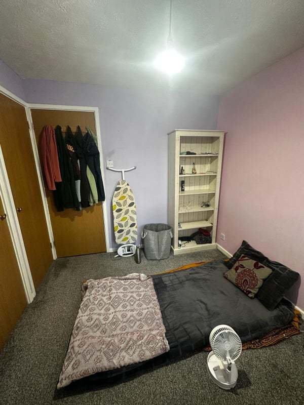 A rental ad for a £1,050/month room in Dunstable, featuring minimal furniture and a mattress on the floor, is ridiculed as "delusional." The room is for two single girls or one couple.