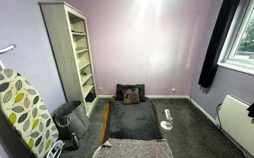 A rental ad for a £1,050/month room in Dunstable, featuring minimal furniture and a mattress on the floor, is ridiculed as "delusional." The room is for two single girls or one couple.