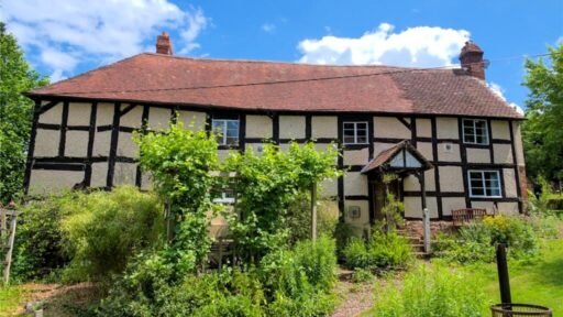 Own a charming 17th-century Tudor cottage with an acre of land in Ludlow, Herefordshire. Featuring 3 bedrooms, a barn, and spacious grounds for £610,000. Perfect for families!