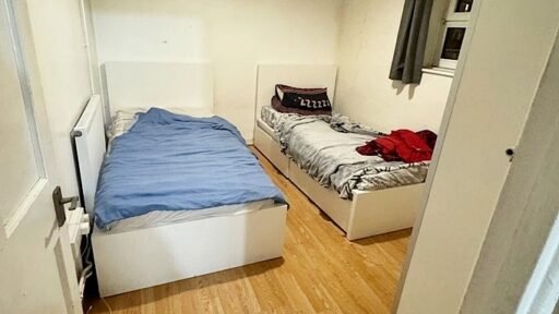 A tiny shared bedroom in Greenwich, London, is listed for £1,500 a month, offering two single beds, minimal space, and bills included, in a vibrant, well-connected location.