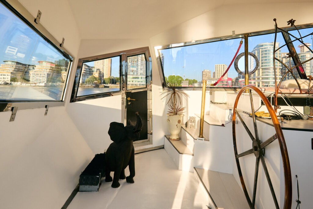 A £1.15m floating sculpture moored in Fulham, Wonderland is a mirrored grain barge turned bohemian home with chandeliers, Thames views and historic artistic charm.