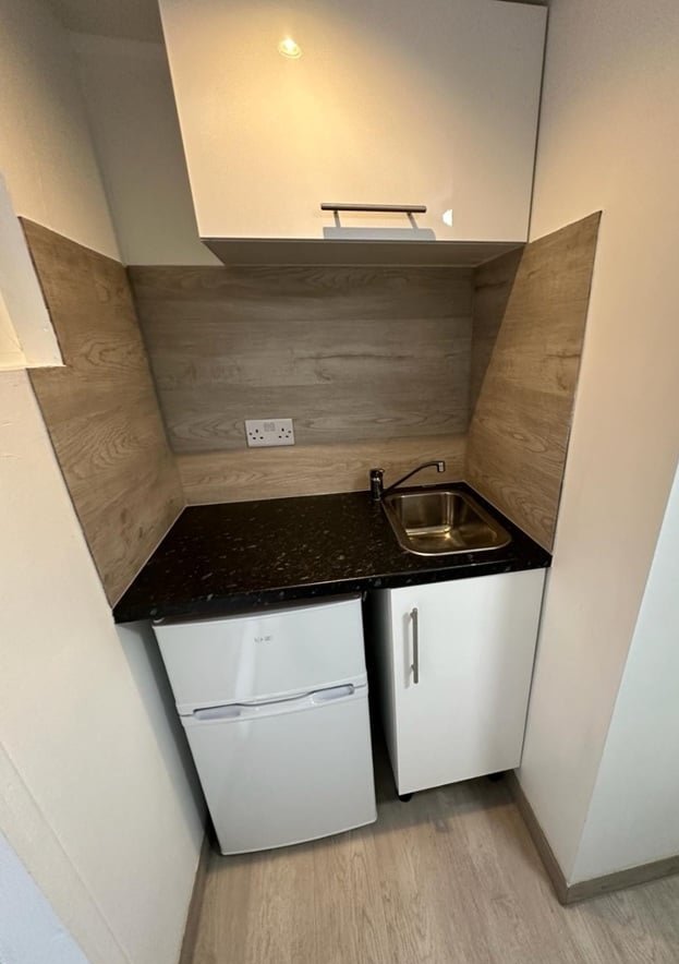 A £750-a-month Canning Town studio with no windows and a curtain for a bathroom door offers minimal space, limited kitchen facilities, and all bills included in rent.