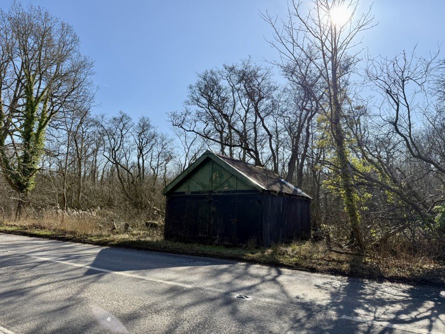 A rundown former boathouse in Horning, Norfolk Broads, with peeling paint and a rusty roof, is up for sale at £25,000, offering restoration potential in a scenic location.