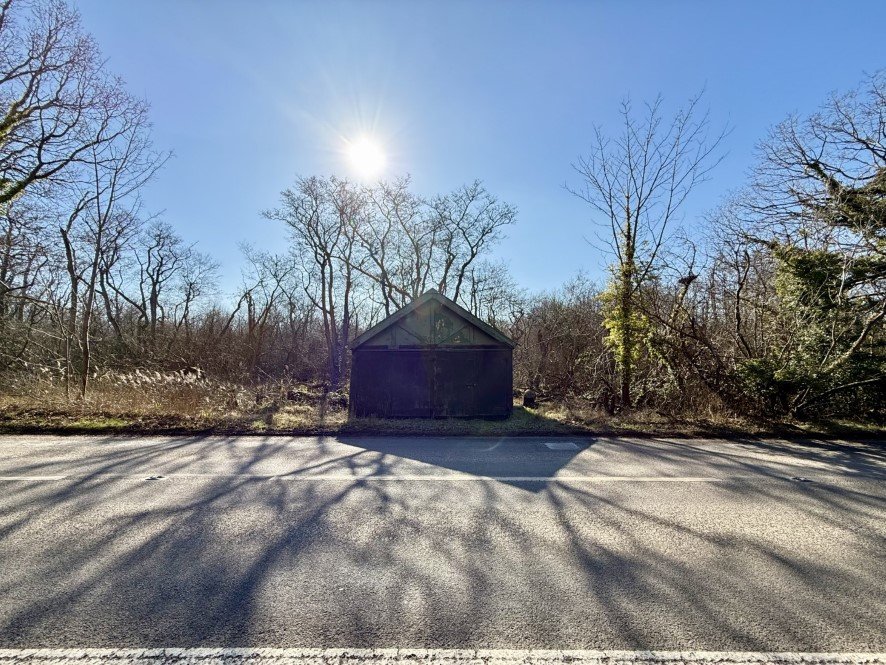 A rundown former boathouse in Horning, Norfolk Broads, with peeling paint and a rusty roof, is up for sale at £25,000, offering restoration potential in a scenic location.