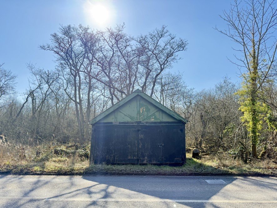 A rundown former boathouse in Horning, Norfolk Broads, with peeling paint and a rusty roof, is up for sale at £25,000, offering restoration potential in a scenic location.