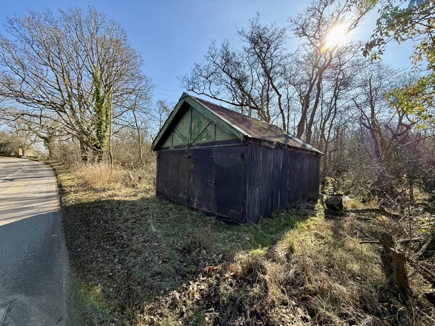 A rundown former boathouse in Horning, Norfolk Broads, with peeling paint and a rusty roof, is up for sale at £25,000, offering restoration potential in a scenic location.