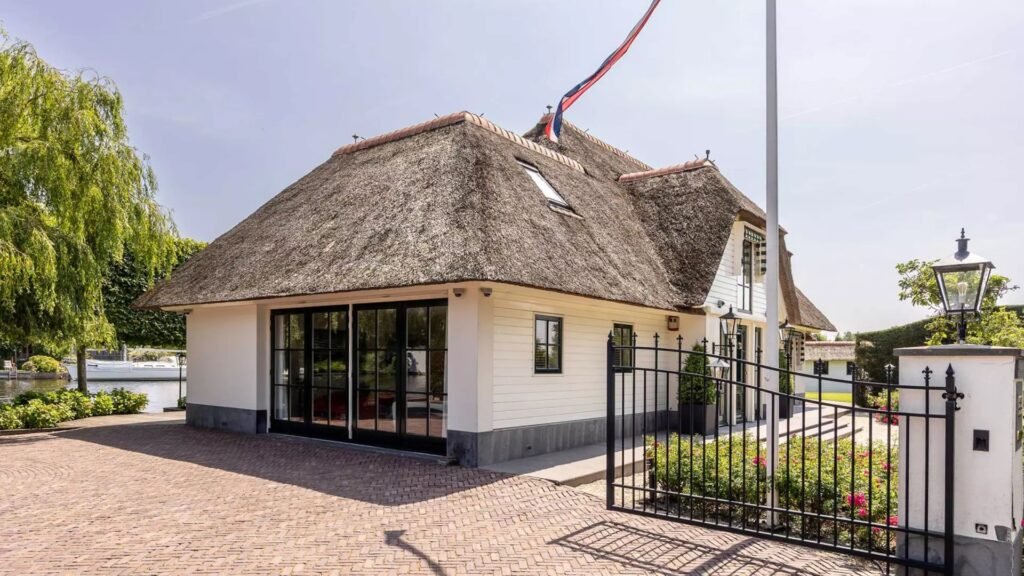 Thatched villa near Amsterdam features luxury interiors, a private boathouse, and a rare home office where you can park two supercars beside your desk.