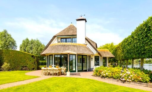 Thatched villa near Amsterdam features luxury interiors, a private boathouse, and a rare home office where you can park two supercars beside your desk.