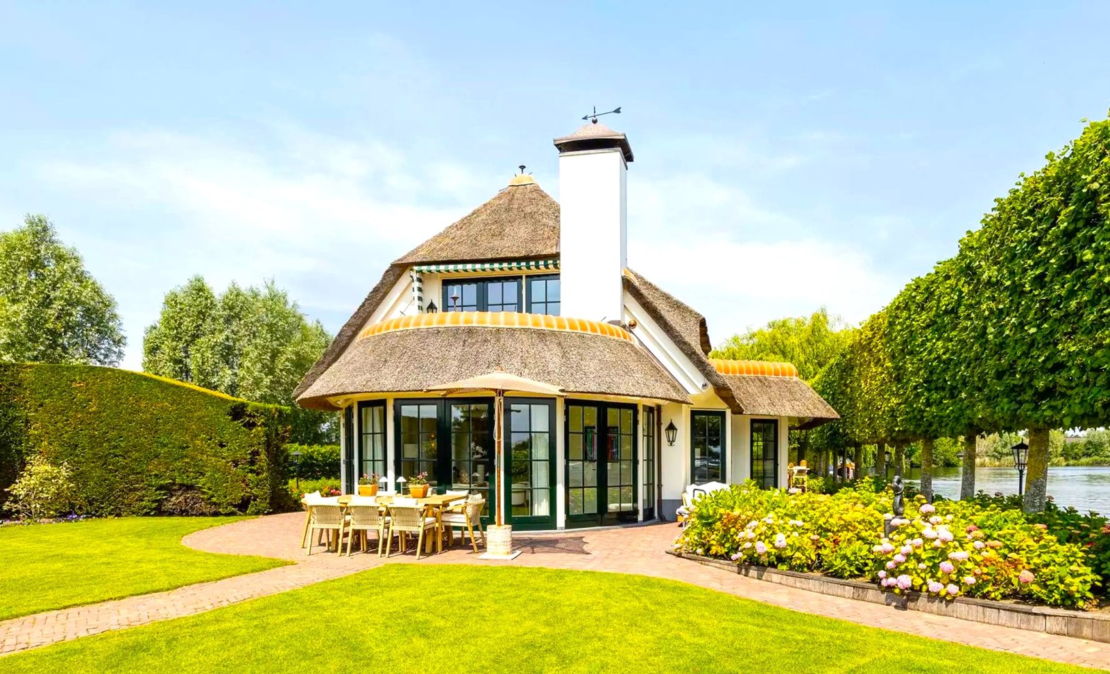 Thatched villa near Amsterdam features luxury interiors, a private boathouse, and a rare home office where you can park two supercars beside your desk.