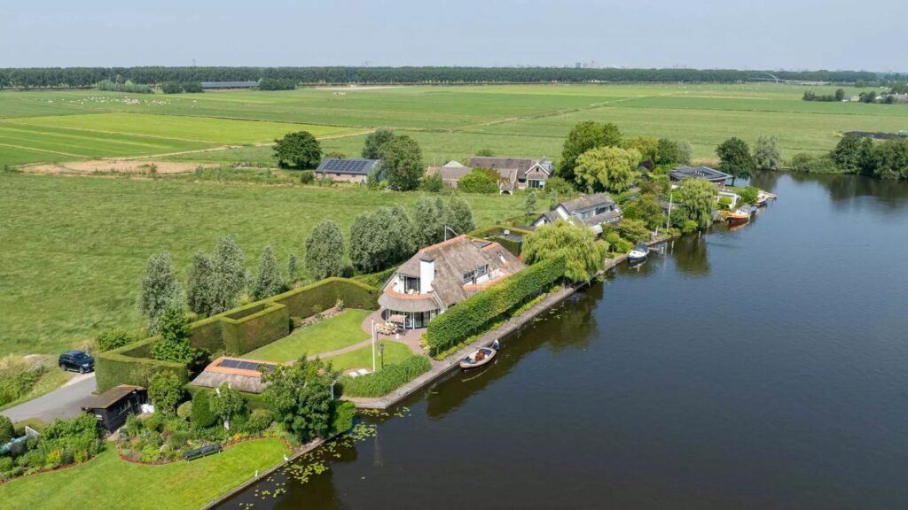Thatched villa near Amsterdam features luxury interiors, a private boathouse, and a rare home office where you can park two supercars beside your desk.