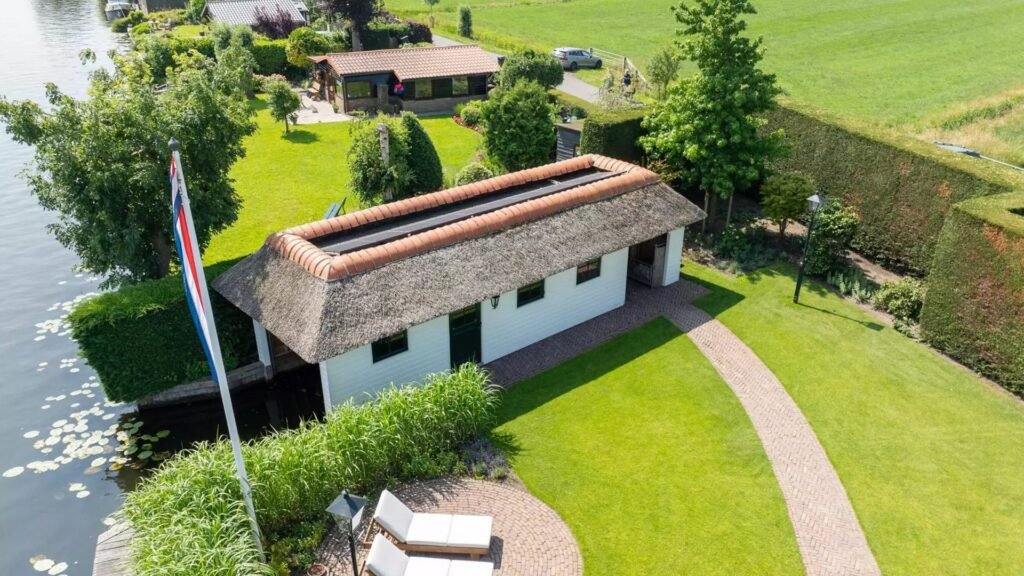 Thatched villa near Amsterdam features luxury interiors, a private boathouse, and a rare home office where you can park two supercars beside your desk.
