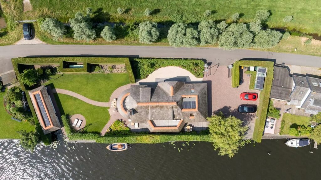 Thatched villa near Amsterdam features luxury interiors, a private boathouse, and a rare home office where you can park two supercars beside your desk.