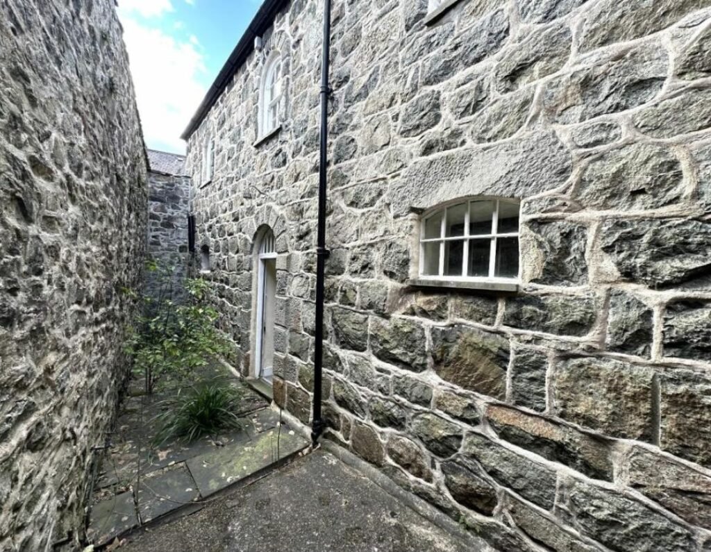A former police station in Dolgellau with four original cells and three courtyards is on the market for £95,000, offering quirky charm and conversion potential.