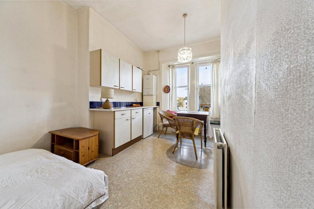 A £99,000 Glasgow flat has hit the market with an unusual twist — the double bed is inside the kitchen, opposite the oven and washing machine, creating a truly quirky layout.