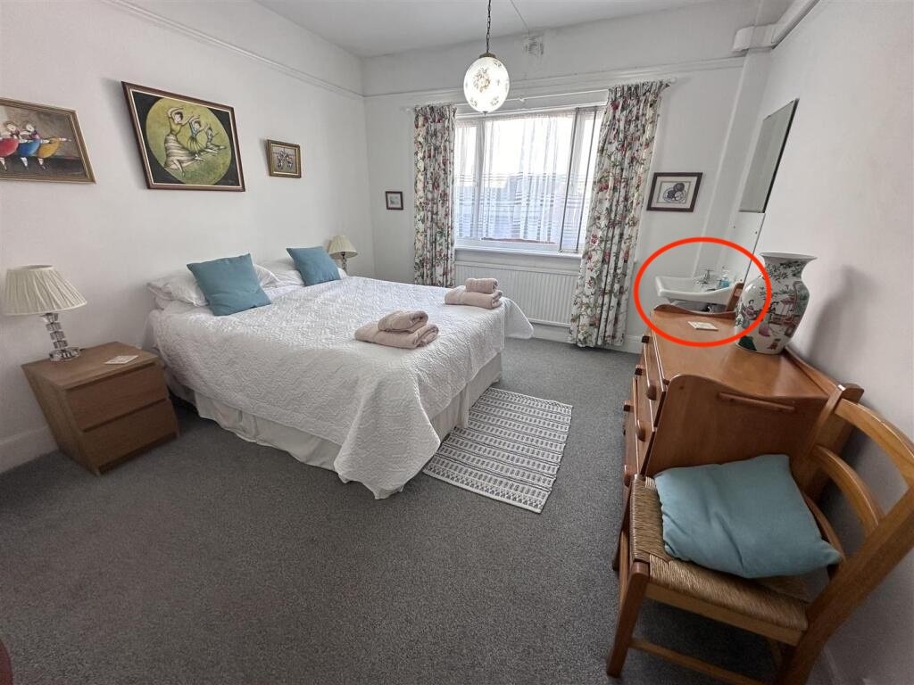 A £1,200-a-month seaside flat with a sink beside the bed has gone viral, leaving renters baffled by the quirky layout, high deposit, and income requirements.