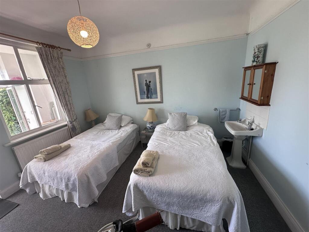 A £1,200-a-month seaside flat with a sink beside the bed has gone viral, leaving renters baffled by the quirky layout, high deposit, and income requirements.