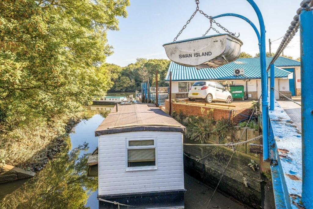 Quirky floating caravan turned houseboat hits the Thames market for £99,950, offering one bedroom, log burner, roof seating and full-time riverside living