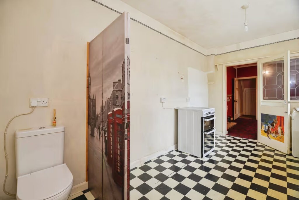 A three-bed home has gone on sale for £110,000 with an "un-loo-sual" twist - a toilet hidden in the kitchen, just feet from the cooker, fridge and sink.